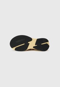 Sport shoe outsole with black rubber surface, yellow midsole, and distinct tread pattern. Textured for grip and stability during movement.