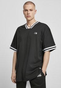 Černé oversized tričko s krátkým rukávem a výstřihem do V, se bílými pruhovanými akcenty na rukávech a logem na hrudi.