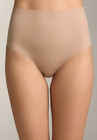 Lenjerie nud bej cu talie înaltă, purtat ă pe șolduri, care evidențiază partea superioară a coapselor și abdomenul inferior pe un fundal simplu.