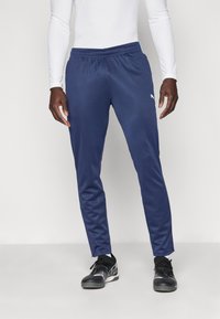 Calças de atletismo azul-marinho com cintura elástica e um corte afunilado, feitas de um tecido leve e suave. Apresentam um pequeno logótipo na coxa.