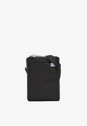 Mała czarna torba na ramię z przednią kieszenią, srebrnym zamkiem błyskawicznym i regulowanym paskiem na ramieniu na białym tle.