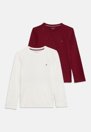 En hvid og en mørkerød langærmet t-shirt med rund hals og lille logo på venstre brystside, lagt fladt på en hvid baggrund.