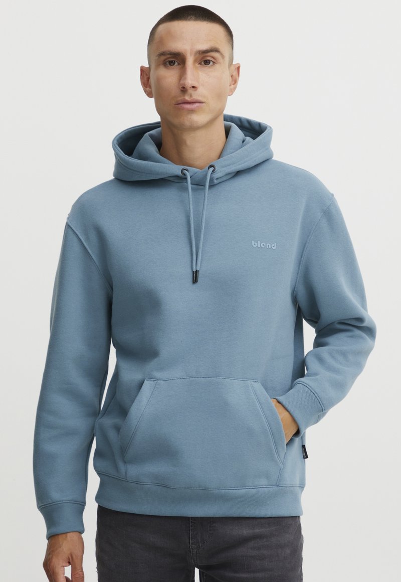 Felpa con cappuccio blu chiaro realizzata in morbido tessuto. Presenta una tasca a marsupio frontale, cappuccio con cordini e un piccolo logo sul petto.