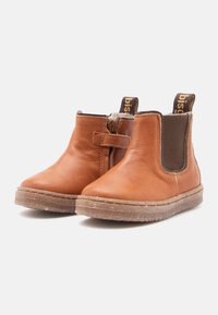 Stivali ankle in pelle marrone con pannelli elastici laterali e un tassello ad anello. Suole in gomma robuste con superficie texture e un design pulito e curvato.