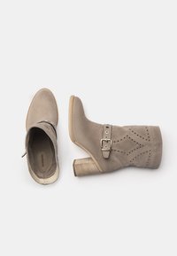 Beige Wildleder-Ankle Boots mit einem Blockabsatz, die mit durchbrochenen Rautenmuster und einem Schnallen-Detail am Schaft ausgestattet sind.