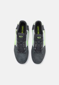Scarpe da ginnastica nere e grigie con pannelli in rete, dettagli verdi e suede testurizzato. Presentano un design con lacci e sezioni perforate.