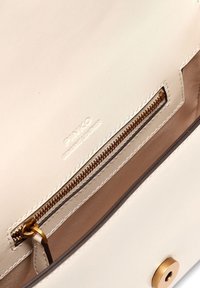 Εσωτερικό μπεζ δερμάτινης τσάντας με χρυσό φερμουάρ, αντίθετη ταμπά επένδυση και ανάγλυφο λογότυπο της μάρκας. Διαθέτει μίνιμαλ και λειτουργικό σχεδιασμό.