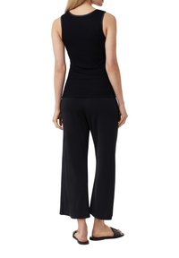 Czarny prążkowany top na ramiączkach połączony z czarnymi spodniami wide-leg. Spodnie mają luźny krój, a top ma okrągły dekolt i dopasowany fason.