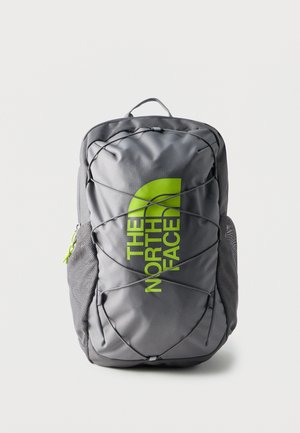 Gray backpack with neon green "The North Face" logo, elastic cords across front, mesh side pockets, and top handle against a white background.
