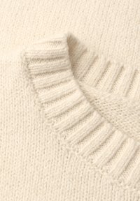 Maglione chunky di colore crema con collo a girocollo ripiegato e a coste, che mostra un morbido tessuto di lana testurizzato.