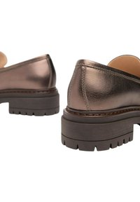 Scarpe in pelle bronzo con tacco basso, punta rotonda e suola in gomma testurizzata con scanalature, evidenziate da dettagli di cucitura visibili.