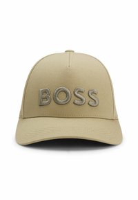 Beige baseball cap with a curved brim, featuring raised, embroidered letters spelling "BOSS" in a lighter shade of beige.
