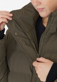 Giacca puffa verde oliva con colletto alto, dotata di zip frontale e bottoni a pressione, che presenta una texture liscia e un design trapuntato.