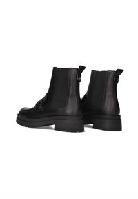Bottines en cuir noir avec des panneaux latéraux élastiques, des semelles épaisses et des tirettes. Texture lisse avec un bout arrondi et des détails minimalistes.