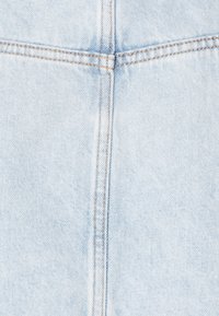 Ljust blå denimtyg med synlig sömnad och en något strukturerad yta. Två vertikala sömmar skapar ett distinkt designelement.