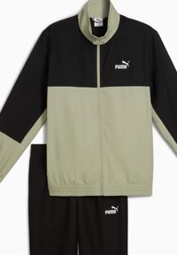 Trainingsanzug mit einer olivgrünen und schwarzen Jacke mit Reißverschluss, hohem Kragen und elastischen Bündchen, kombiniert mit schwarzen Hosen mit elastischem Bund, beide mit Puma-Logo.