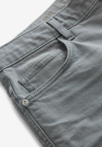 Pantaloni in denim grigio con tasca frontale, passanti per la cintura e una sottile texture. Presentano un rivetto in metallo e dettaglio di cuciture lungo le cuciture.