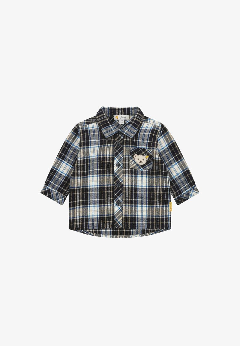Chemise à manches longues pour enfant avec un motif écossais en noir, blanc et bleu, et un petit écusson en forme de visage d'ours sur la poche poitrine.