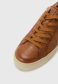 Baskets en cuir marron avec une finition texturée, dotées de lacets ton sur ton et d'une semelle en caoutchouc clair. Bout rond avec un design minimaliste.