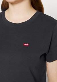 Fekete, rövid ujjú pamut póló, kerek nyakkivágással. Bal mellen található egy apró piros Levi's logó címke.