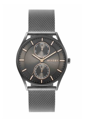 Reloj de pulsera Skagen negro con correa de malla, marcadores horarios dorados, subesferas de día y fecha, y manecillas doradas de hora, minuto y segundo.