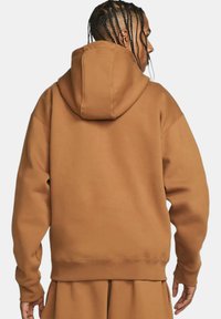 Felpa con cappuccio marrone realizzata in tessuto morbido. Caratterizzata da una vestibilità comoda, tasca a marsupio e polsini e orlo a costine. Semplici dettagli cuciti.