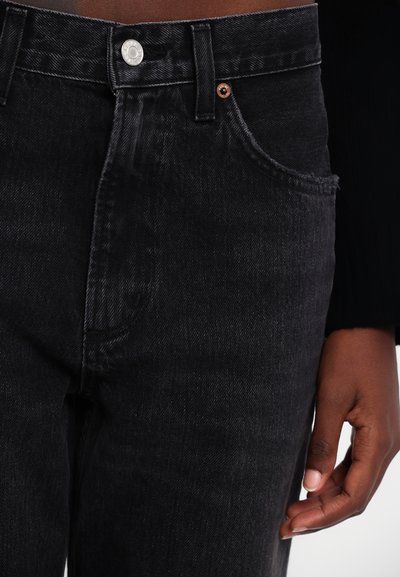 Black denim jeans featuring a mid-rise waist, five-pocket design, and a frayed hem. Finished with a silver button and sturdy stitching.