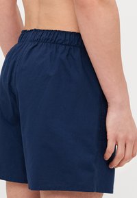 Navy blå bomullsshorts med elastisk midje, med en avslappet passform og diskrete sømdetaljer. Jevn tekstur, midt på låret lengde.