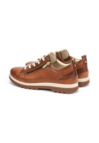 Chaussures en cuir marron avec une texture lisse, dotées d'une fermeture éclair sur le côté, de lacets blancs et d'une semelle en caoutchouc blanc avec un motif de traction.