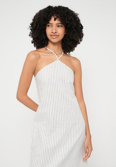 Prugasta halter obleka v beli barvi z mornarsko modrimi črtami, z zasnovo v obliki križa na izrezu in sproščenim krojem.
