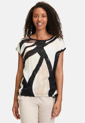 Short-sleeve top in cream with black and beige abstract design. Features a rounded neckline and adjustable side drawstring for fit.