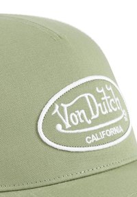 Gorra verde con diseño redondeado, fabricada con tela texturizada, con un logo ovalado bordado en blanco que dice "Von Dutch CALIFORNIA".