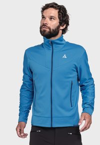 Blaue Zip-Jacke aus strukturiertem Stoff, mit hohem Kragen, diagonalen Nähdetails und zwei mit Reißverschluss versehenen Seitentaschen.