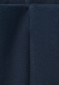 Tissu tricoté bleu foncé avec une couture verticale visible au centre et un bord plié en haut.