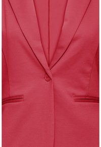 Ühe nupuga korallroosa bleiser, millel on sälguga krae ja kaks horisontaalset taskut, näidatud lähedalt.