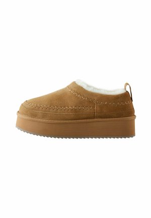 Scarpe mocassino in suede marrone con foderato in pelliccia, punta rotonda e suola piattaforma spessa e rigata. Presentano cuciture decorative e un'etichetta posteriore.