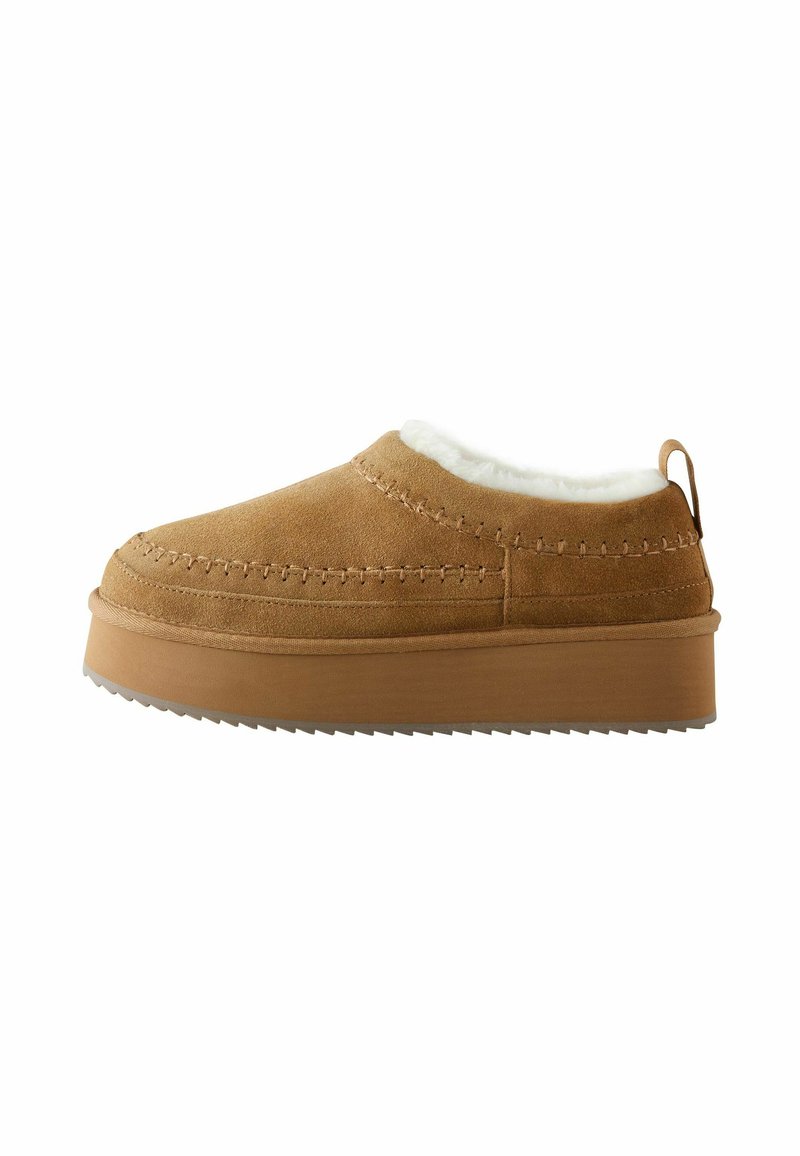 Smeđe semiš cipele na slip-on s krznastom unutrašnjošću, okruglim prstom i debelim, nazubljenim potplatom. Imaju dekorativne šavove i stražnju traku.