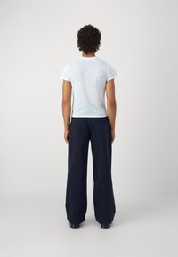 Světle modré tričko s krátkým rukávem a texturovaným povrchem, doplněné širokými námořnickými kalhotami, z pohledu zezadu na neutrálním pozadí.