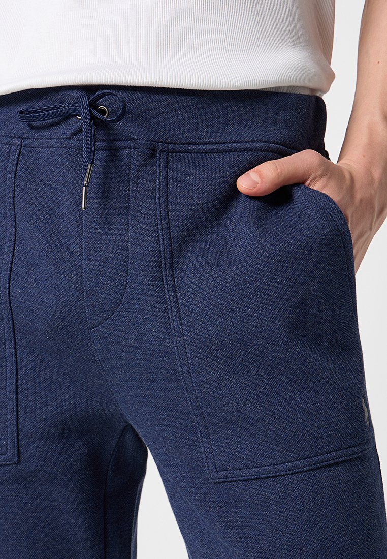 Granatowe dresy z teksturowanej tkaniny, z bocznymi kieszeniami, elastycznym pasem ze sznurkiem oraz widocznymi szwami.