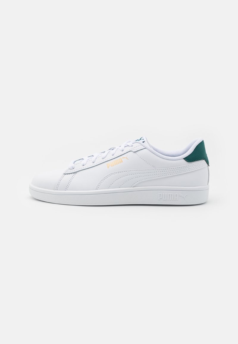 Baskets basses blanches Puma avec design à lacets, logo doré sur le côté et accent vert sur le col du talon, vues de côté extérieur.