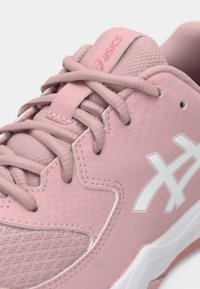 Hellrosa Sportlichschuhe aus Mesh- und Synthetikmaterial, flache Schnürsenkel, ein weißes Logo und strukturierte Details im Obermaterial.