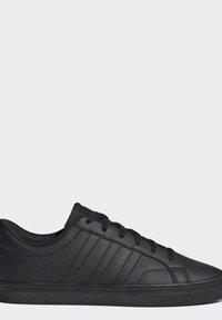 Baskets basses noires avec lacets noirs, languette texturée et triple bandes signature sur le côté, sur un fond gris uni.