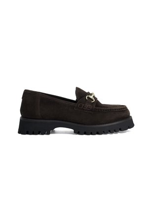 Mocassin en daim marron foncé avec une semelle en caoutchouc noire épaisse et un détail de boucle en métal argenté sur le dessus, montré de côté.