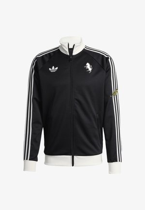 Musta vetoketjullinen urheilutakki, jossa on sileä kangas, valkoiset raidat, korkea kaulus sekä logot rinnassa ja hihassa.