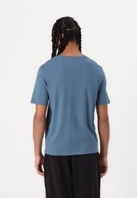 Short-sleeve t-shirt in soft, muted blue fabric, featuring a crew neck and a relaxed fit. Smooth texture with no visible patterns or accents.