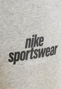 Szürke pamut anyagon fekete színnel van nyomtatva a "nike sportswear" felirat, alatta pedig fehérrel a "ESTABLISHED 1972" felirat. Puha tapintású, laza stílusú.