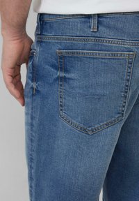 Jasnoniebieskie dżinsy o prostym kroju, z wzmocnionymi szwami, jedną tylną kieszenią z detalami w szwie i gładką fakturą.