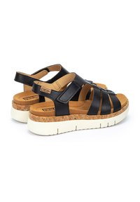 Sandalias de cuero negro con media suela de corcho y suela de goma blanca. Cuentan con correas ajustables y un diseño de punta abierta.