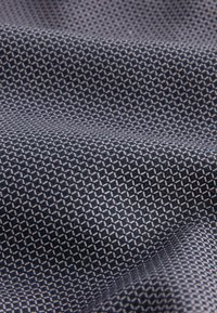 Geometrikus mintázatú textil, kis gyémántokkal, sötétkék és krémszínű árnyalatokban, sima, enyhén texturált felülettel.