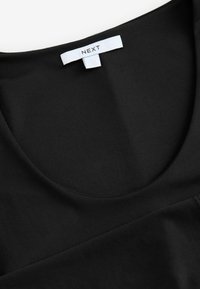 Top nero aderente con scollatura ampia, realizzato in tessuto liscio. Presenta un'etichetta con il marchio "NEXT" sul retro.
